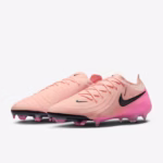 Side view of Nike Phantom GX 2 Elite soccer cleats in a peach and black colorway, designed for firm ground control and precision passing.
